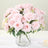 Pink artificial roses in a clear vase, elegantly arranged for display.