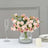 Pink and purple artificial flower bouquet in a glass vase on a table.
