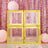 Yellow decorative boxes on a pink sequin backdrop with balloons and flowers.