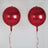 Red glossy balloons with red ribbons on a plain background.