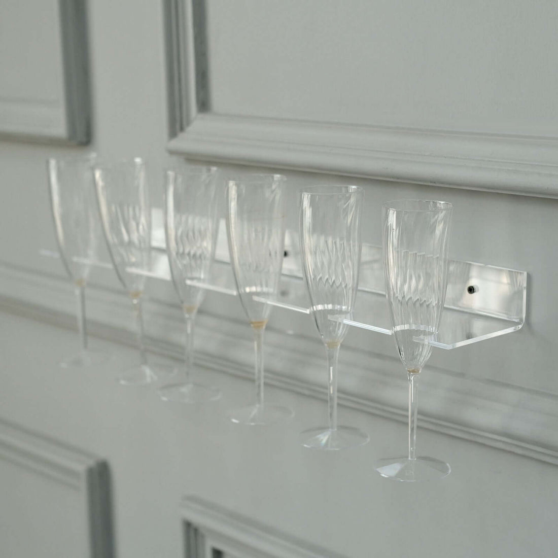 Clear champagne flute rack displaying six elegant glasses.