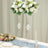 Elegant floral arrangements in tall glass vases on a decorated table setting.