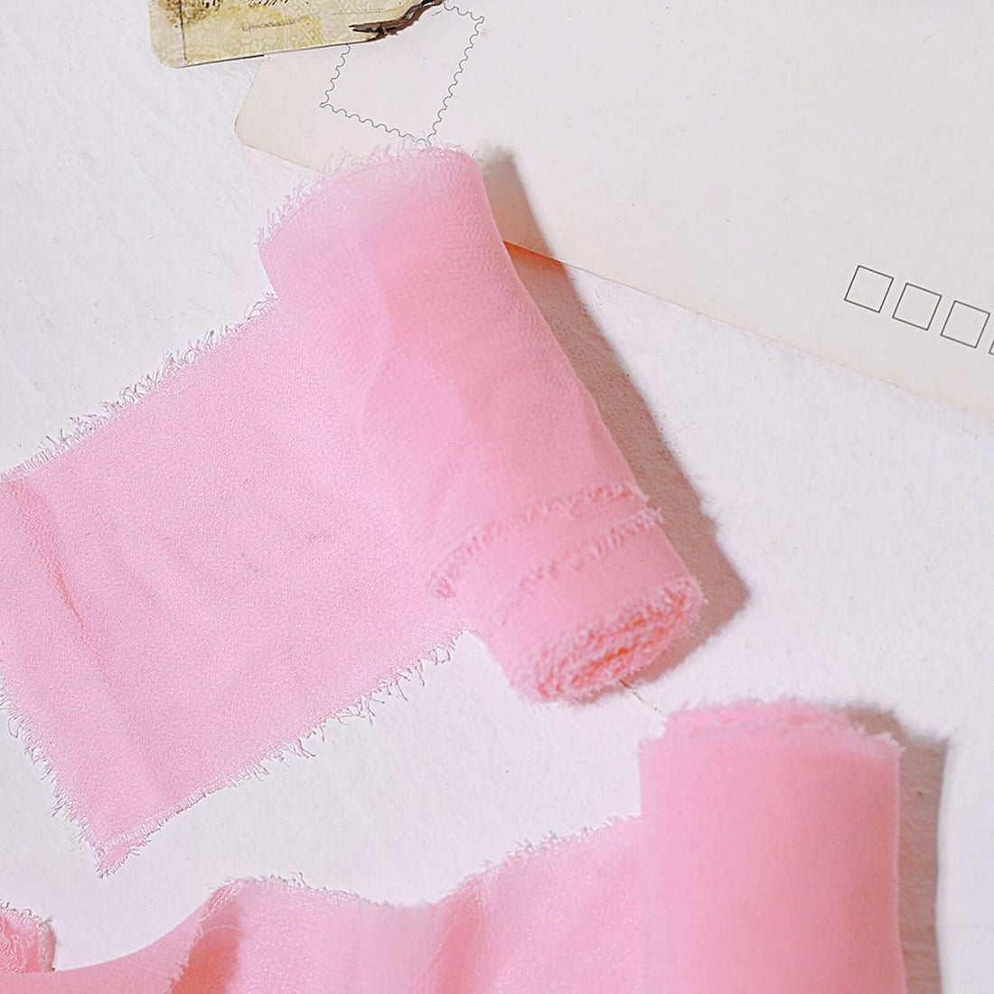 Pink chiffon fabric rolls on a white background.