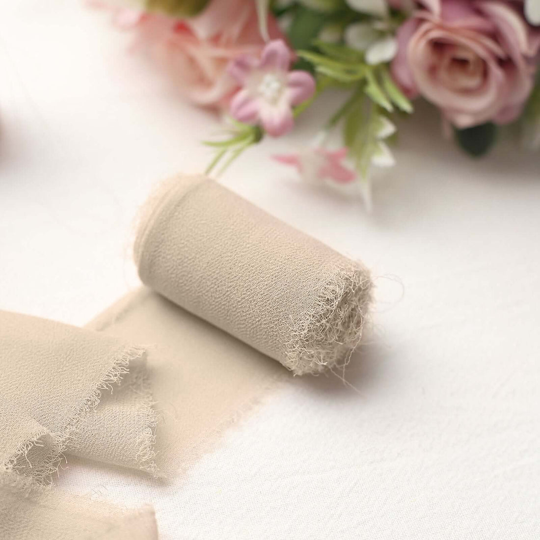 Beige fabric roll with frayed edges on a soft surface