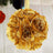 Golden fabric flower ball decoration hanging on ribbon.