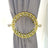 Gold decorative curtain tieback with intricate design and crystal accents.