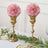 Pink rose floral arrangements in gold vases on a decorated table