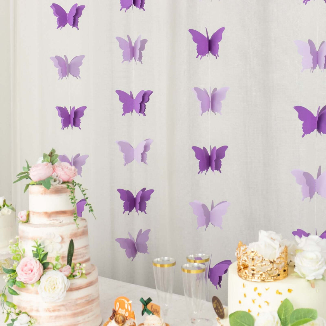 Purple butterfly garland decoration for events with cake and floral arrangements.