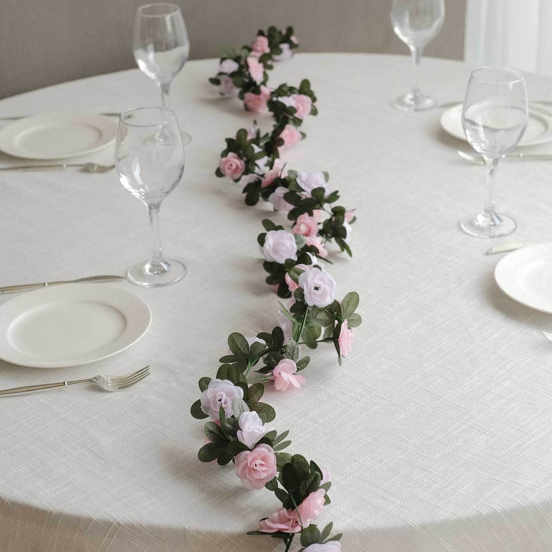 Floral table runner with pink and white roses on a dining table.