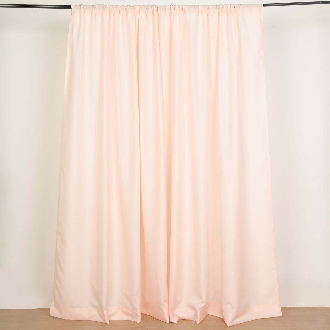 Peach-colored curtain draped on a rod in a studio setting