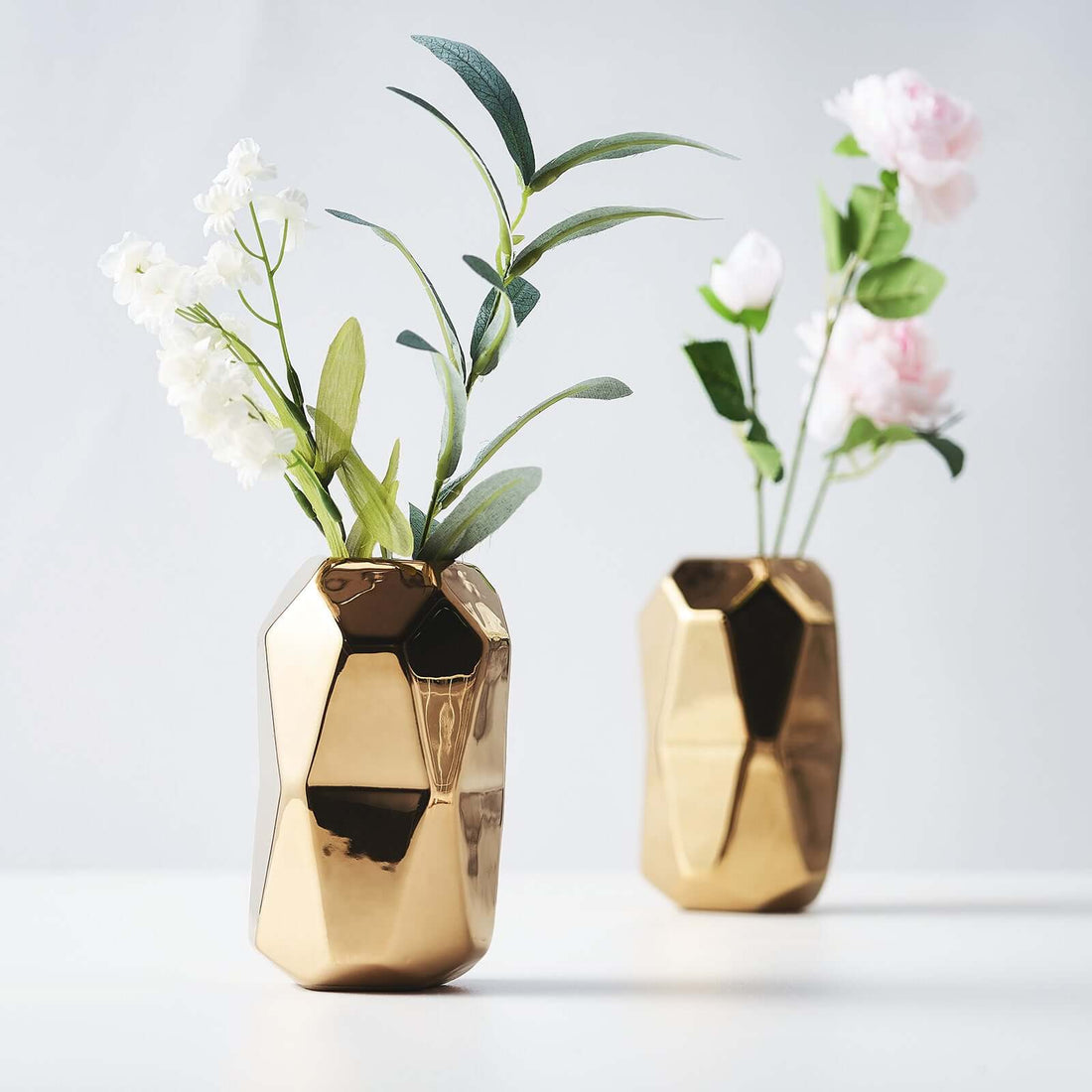 Gold geometric vases with flowers on a white background