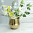Gold vase with white and yellow flowers arranged artistically.