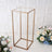 Gold metal display stand with a clear top and elegant floral arrangements.