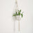 Macramé plant hanger with a white pot and green fern