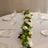 Elegant table setting with white roses and greenery on a round table.