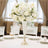 Elegant white floral centerpiece in a sparkling vase on a dining table.