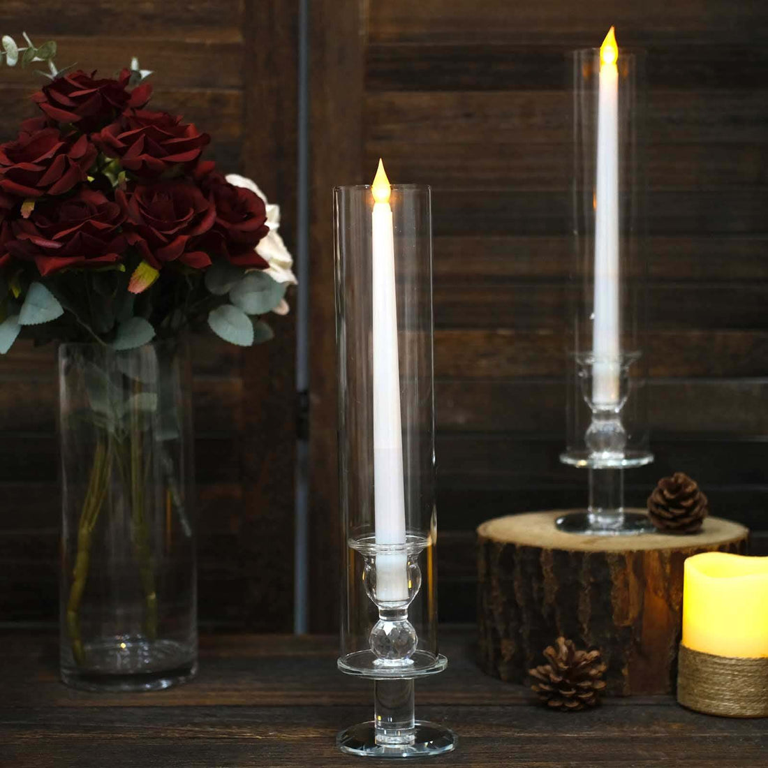 Elegant glass candle holders with white candles and decorative roses.