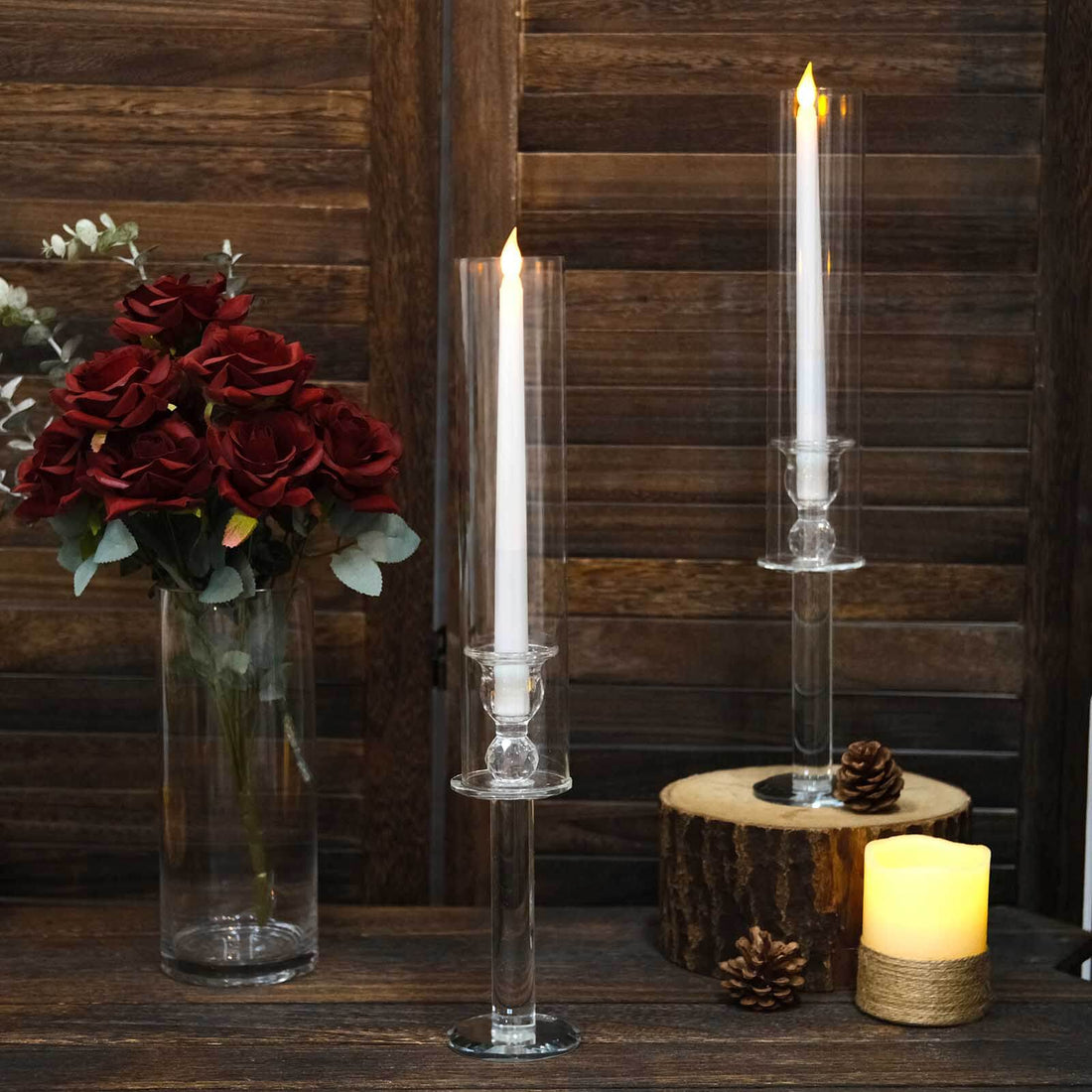 Elegant glass candle holders with white candles and decorative flowers.