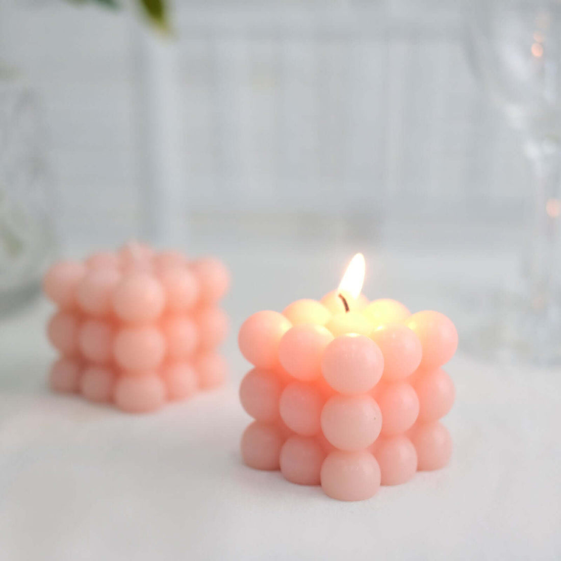 Pink bubble candle with a lit wick on a soft background.