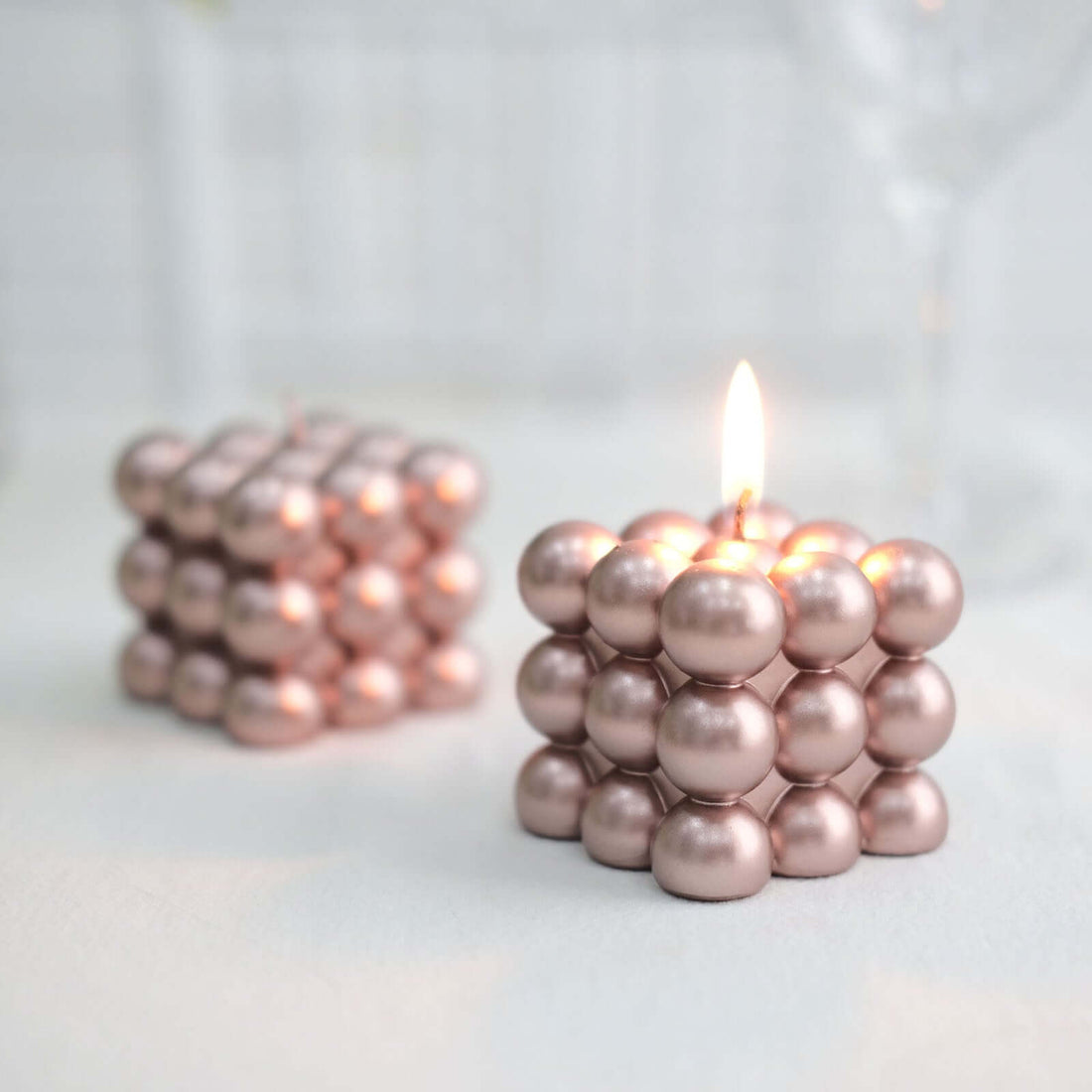 Rose gold bubble candle in a unique geometric design, lit and unlit.