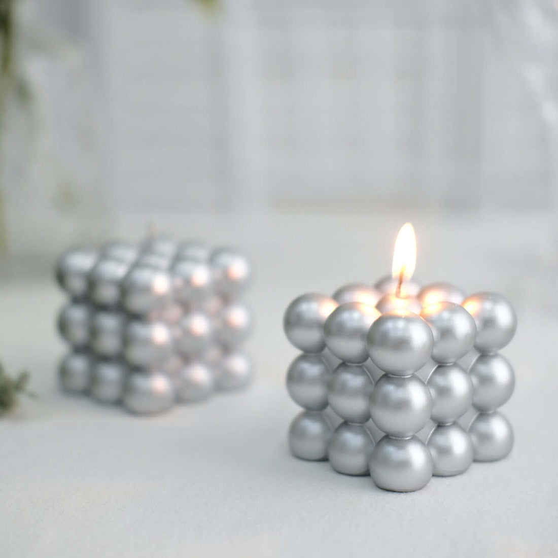 Silver decorative candle in a unique spherical design, lit and glowing.