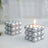 Silver decorative candle in a unique spherical design, lit and glowing.