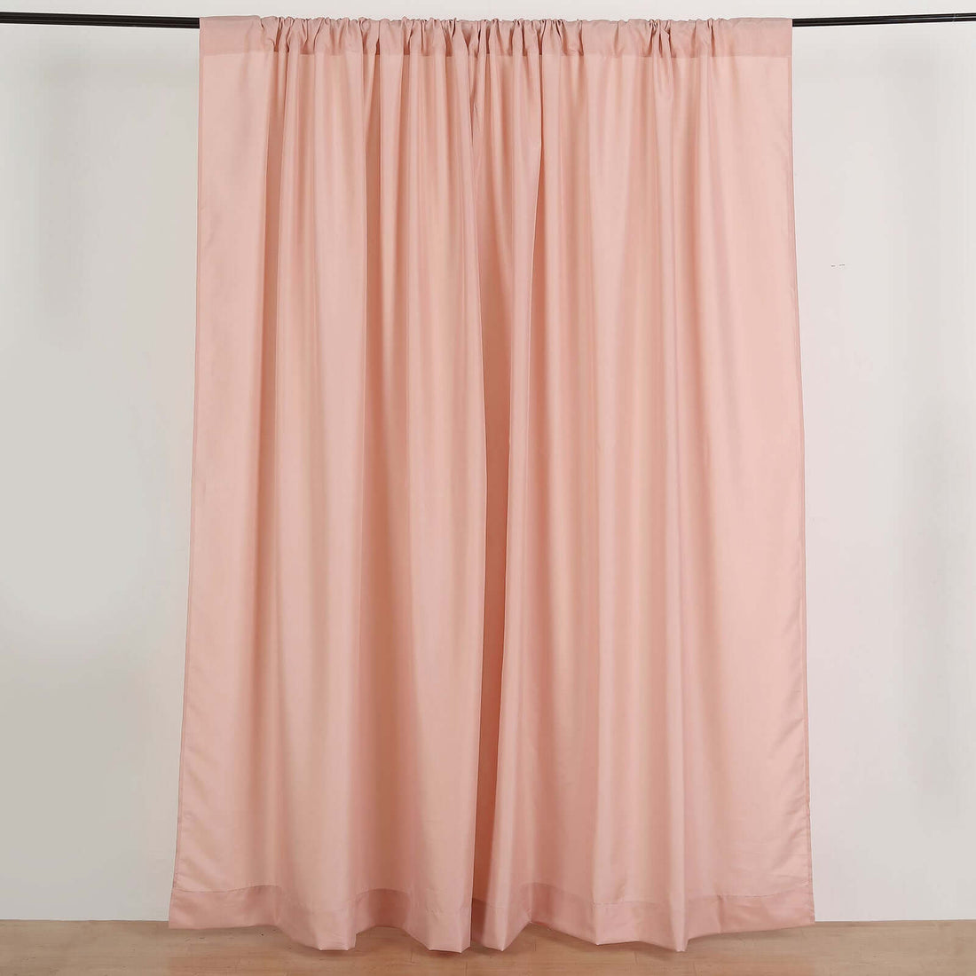 Soft pink curtain draping elegantly against a plain background.