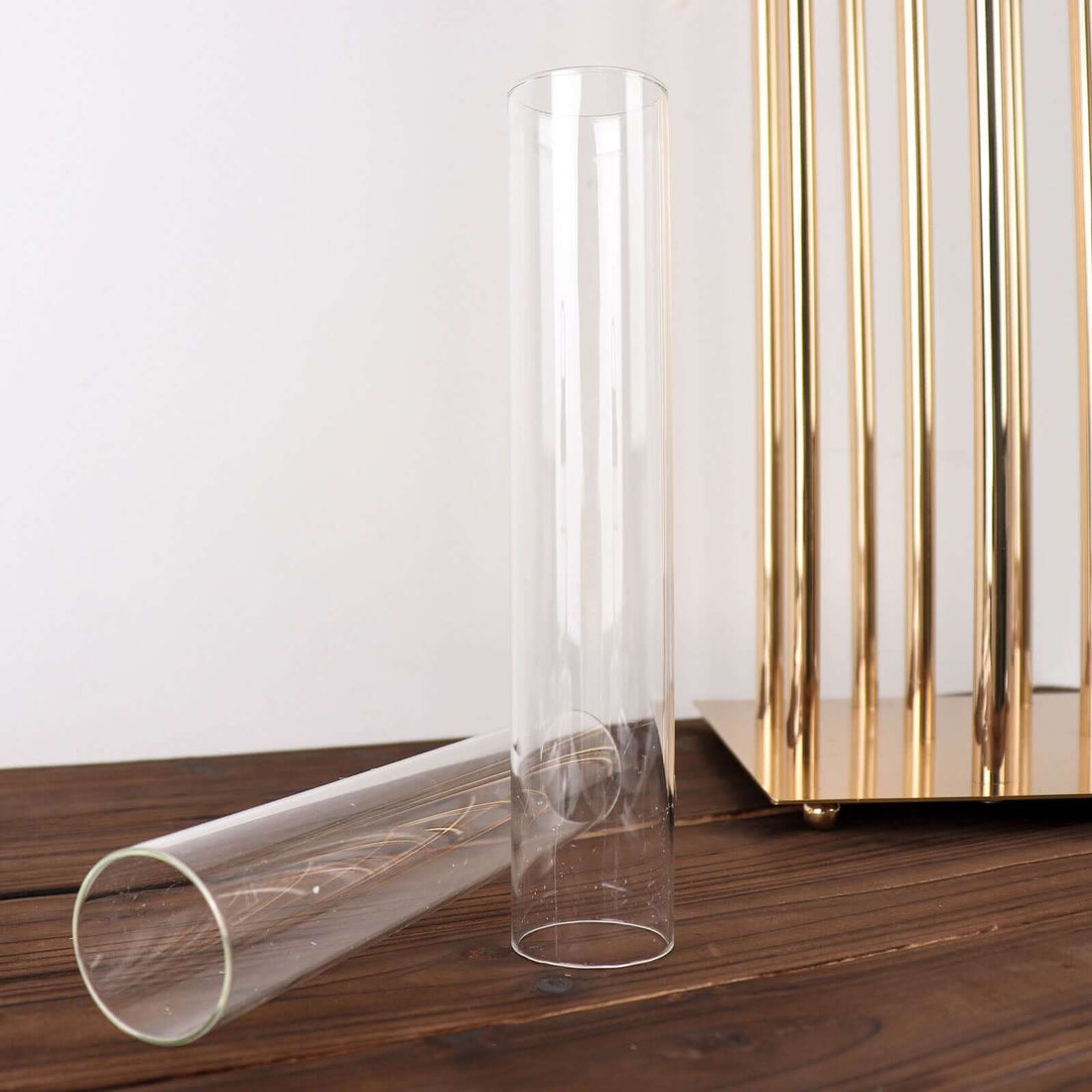 Clear glass vases on a wooden surface with golden decor in the background.
