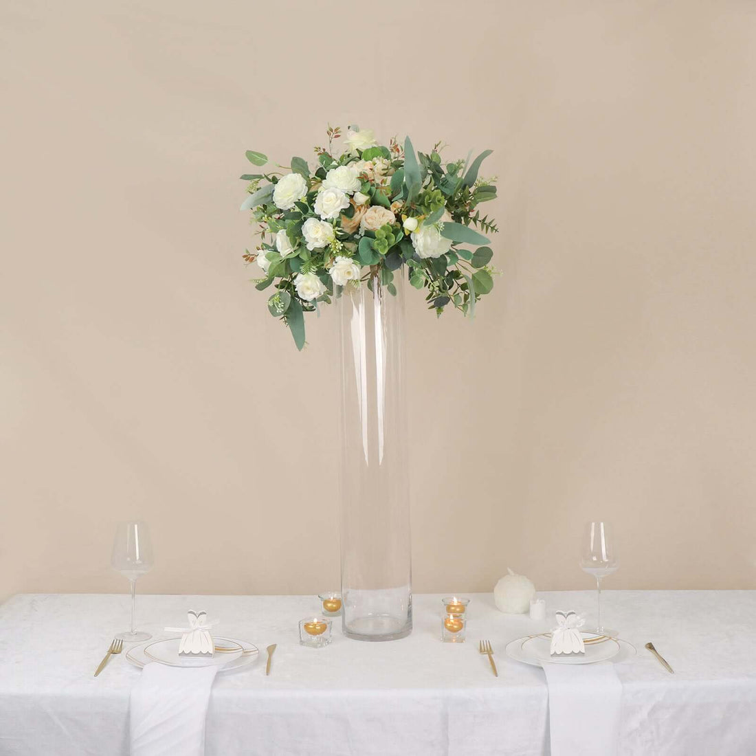 Tall glass vase with a floral arrangement on a dining table setting.