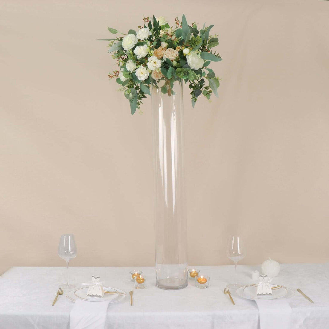 Elegant floral arrangement in tall glass vase on a dining table.