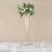 Elegant floral arrangement in tall glass vase on a dining table.