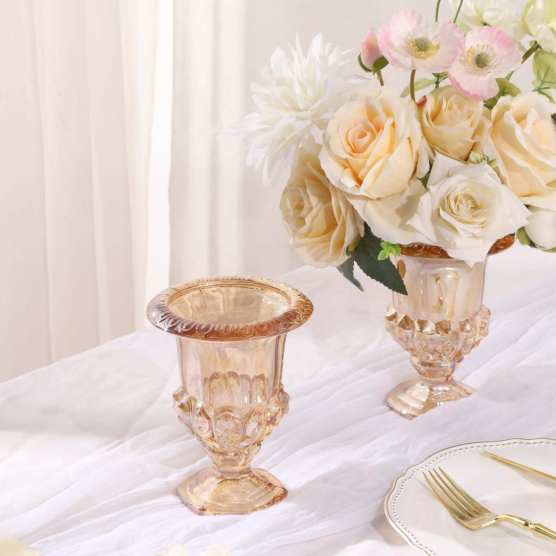 Elegant vintage glass vases with flowers on a textured table setting.