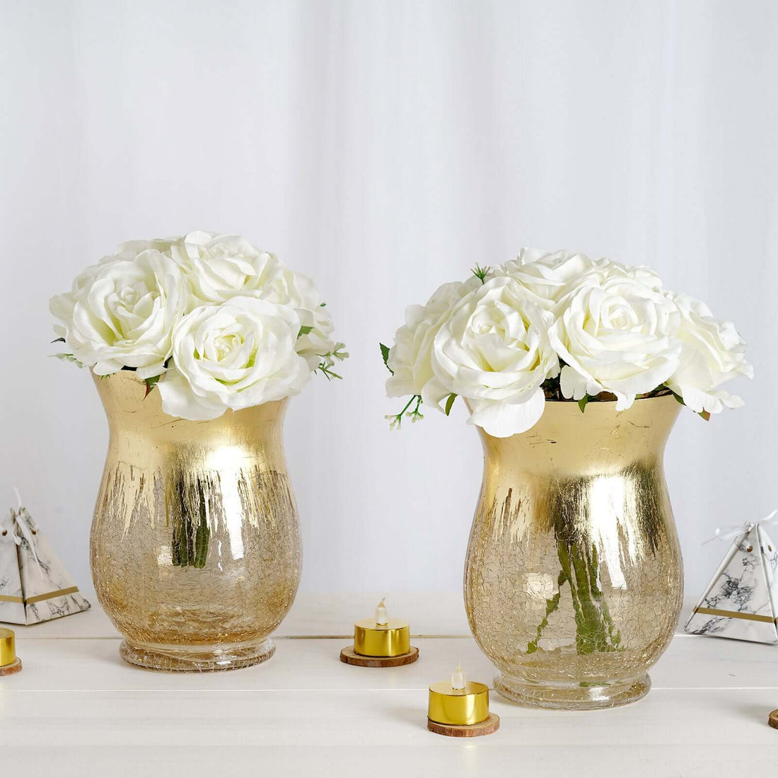 Gold vases with white roses, elegant decor for any setting.