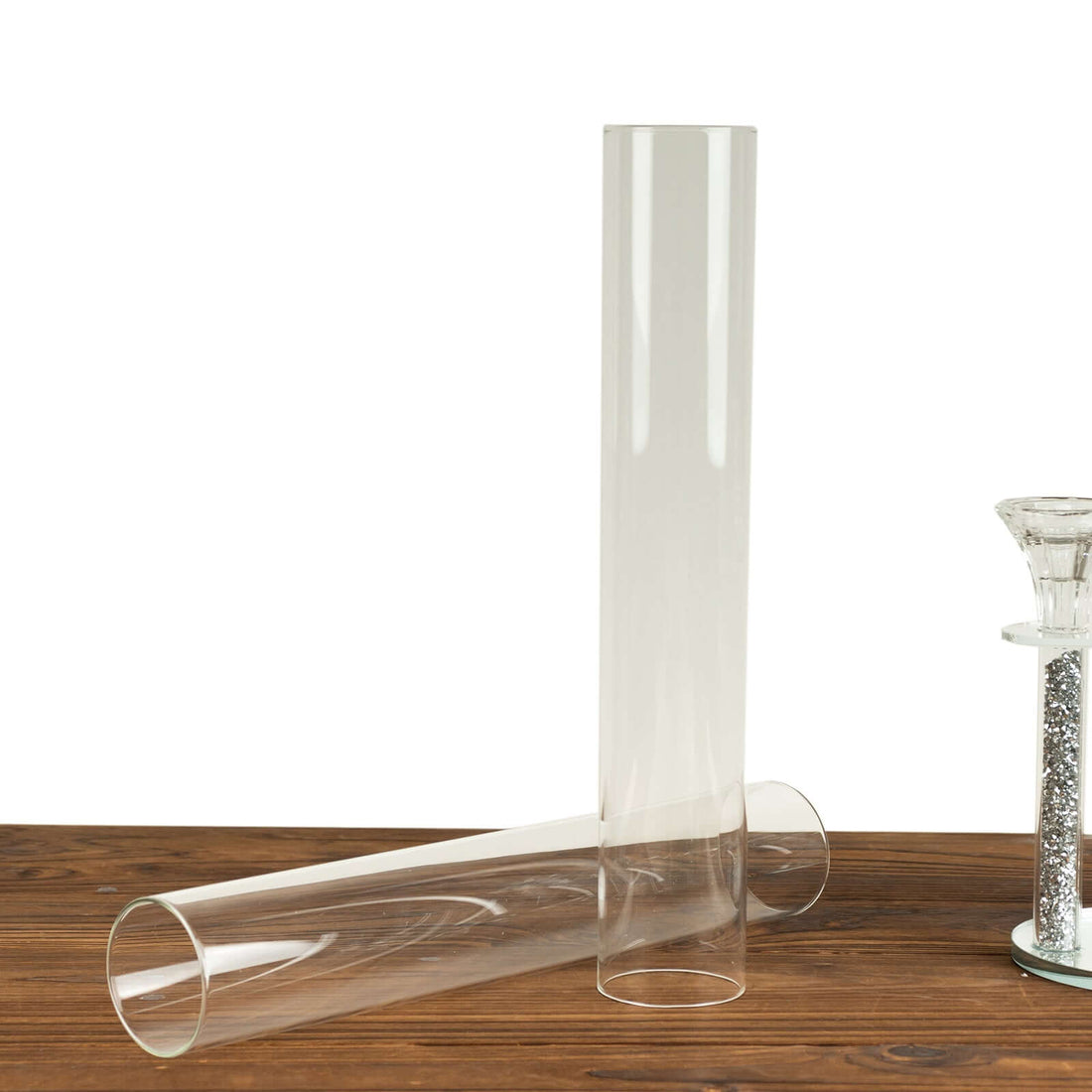 Clear glass cylinder vases on a wooden surface.