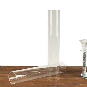 Clear glass cylinder vases on a wooden surface.