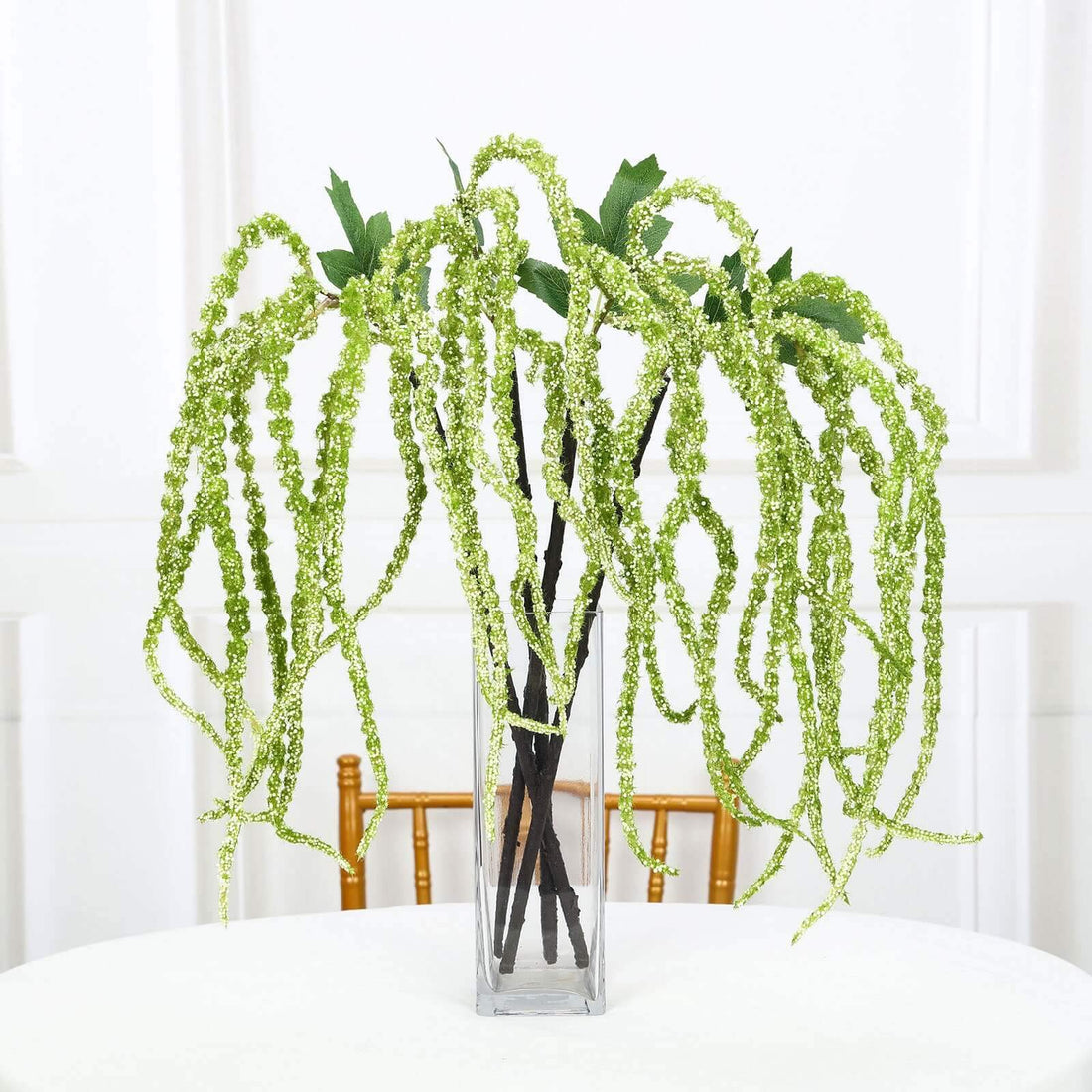 Artificial green hanging plant in a clear vase.
