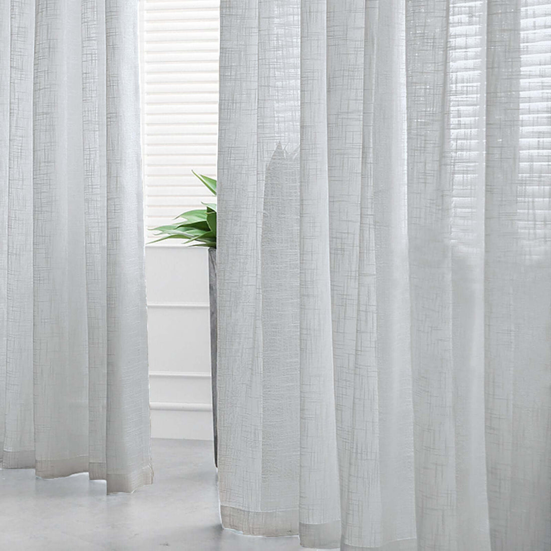 Lightweight sheer curtains draping elegantly in a bright room.