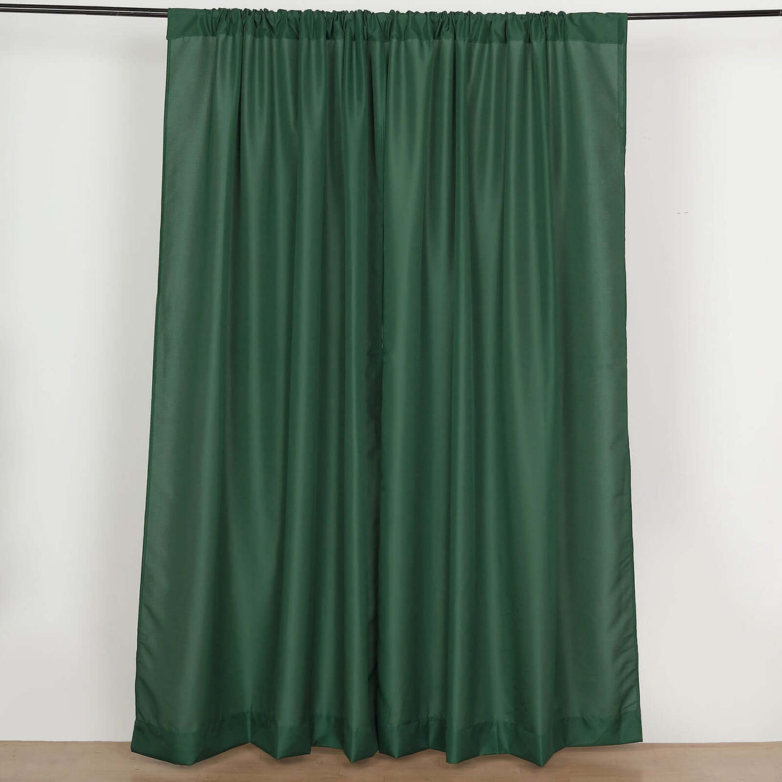 Green curtain panel with a pleated design on a white backdrop