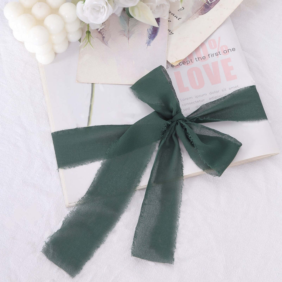 Dark green sheer ribbon elegantly tied on a book with decorative elements.