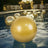 Gold inflatable beach balls floating in a pool with blurred lights in the background.