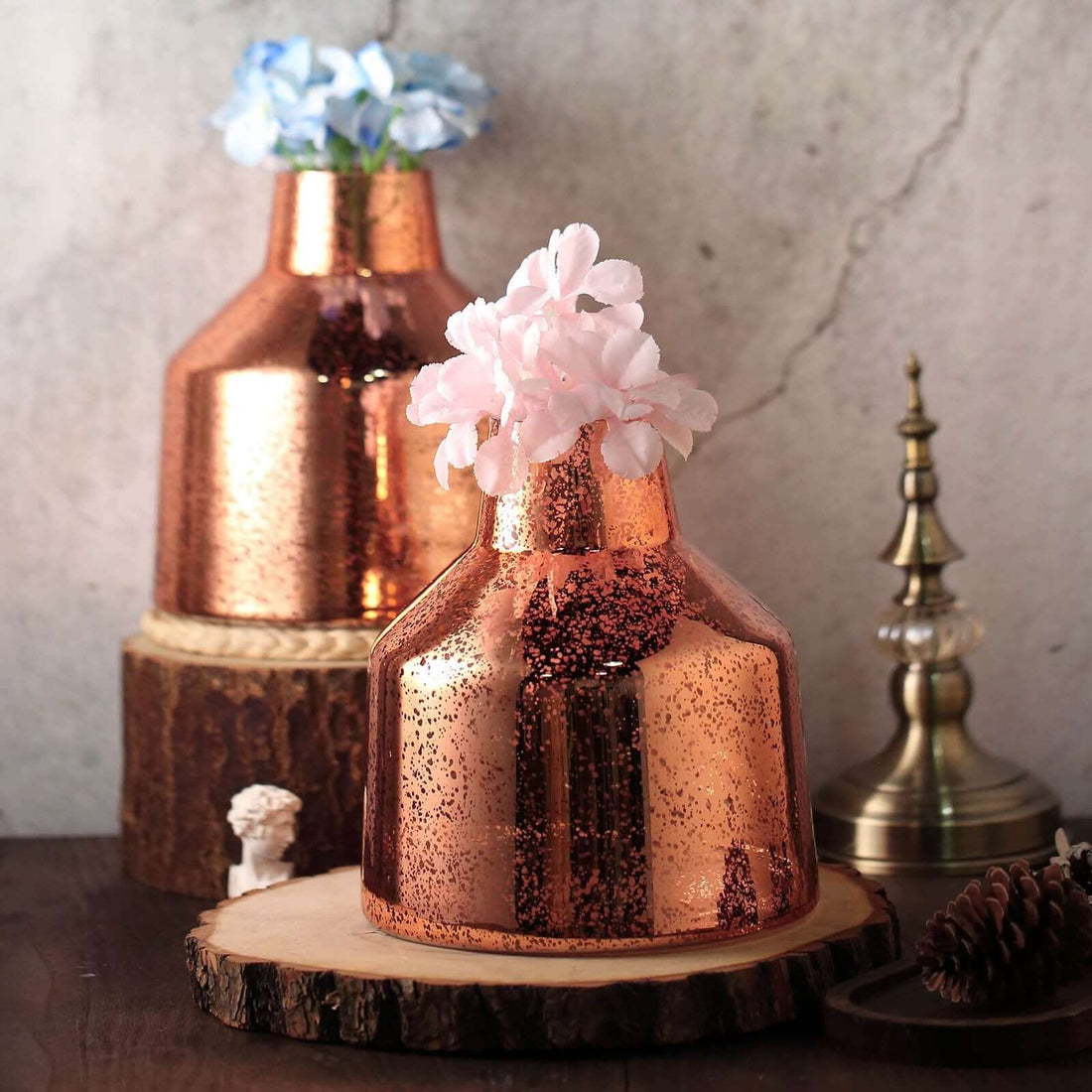 Copper vases with flowers on wooden coasters, styled decor for home interiors.