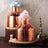 Copper vases with flowers on wooden coasters, styled decor for home interiors.