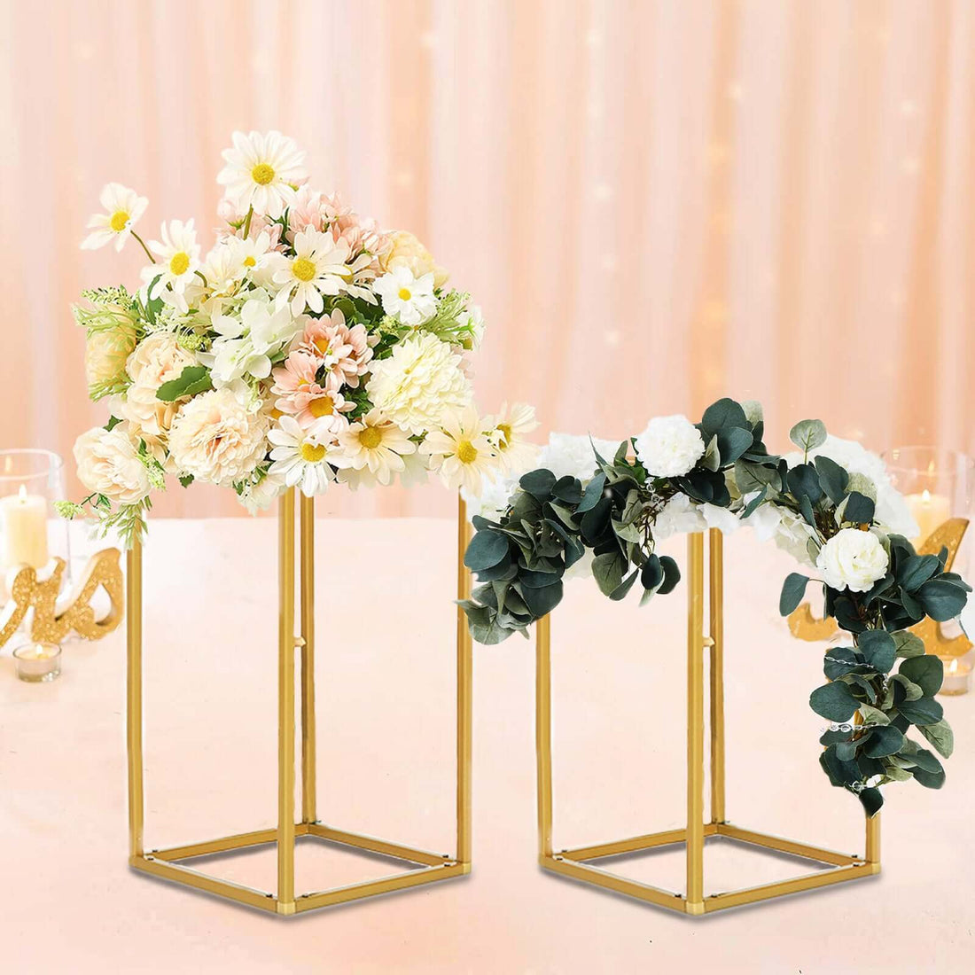 Decorative floral arrangements in elegant gold stands against a soft pink background.