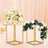 Decorative floral arrangements in elegant gold stands against a soft pink background.