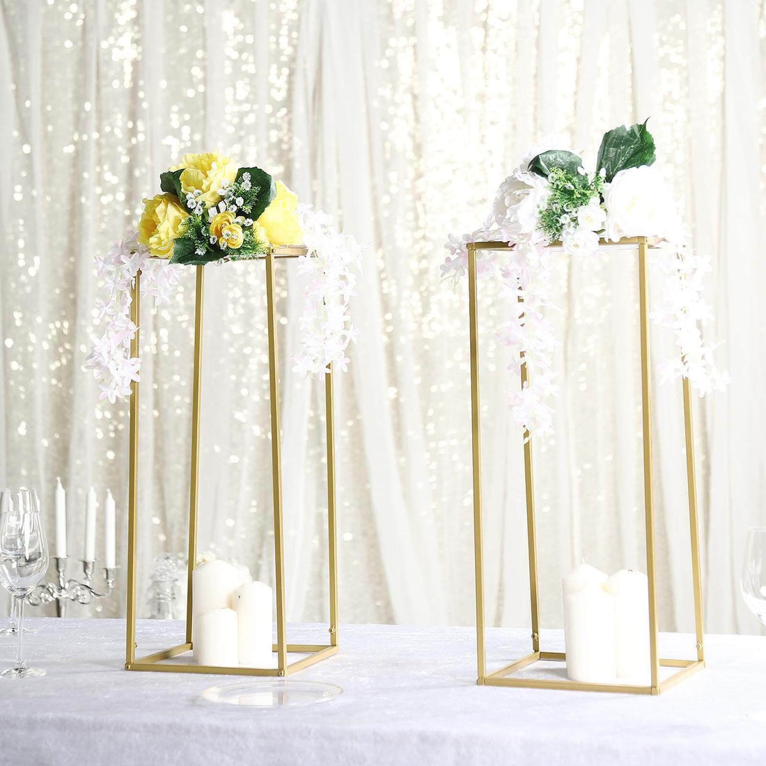 Elegant floral centerpieces in gold candle holders on a table.