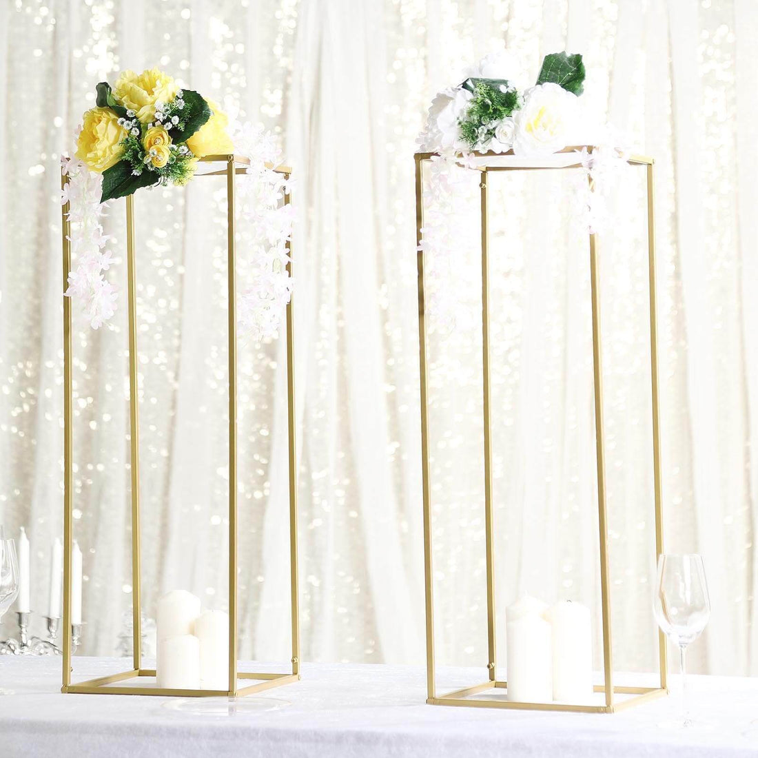 Gold floral display stands with candles and flowers on a sparkling backdrop.