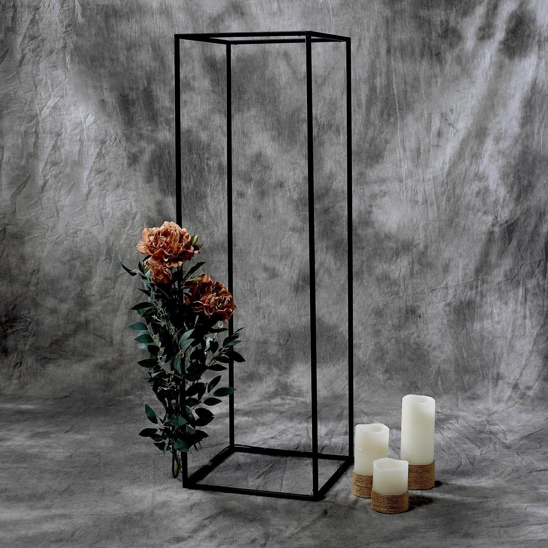 Black metal display stand with flowers and candles on a textured background.