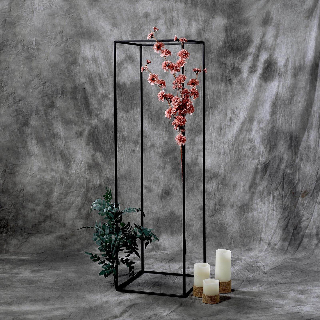 Decorative floral display with candles in a modern black frame.