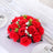 Red artificial rose bouquet with white flowers on a table setting.