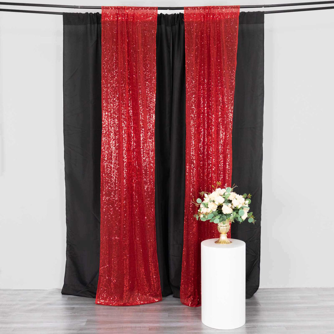 Red sequin backdrop curtains with black drapes and a white pedestal table.